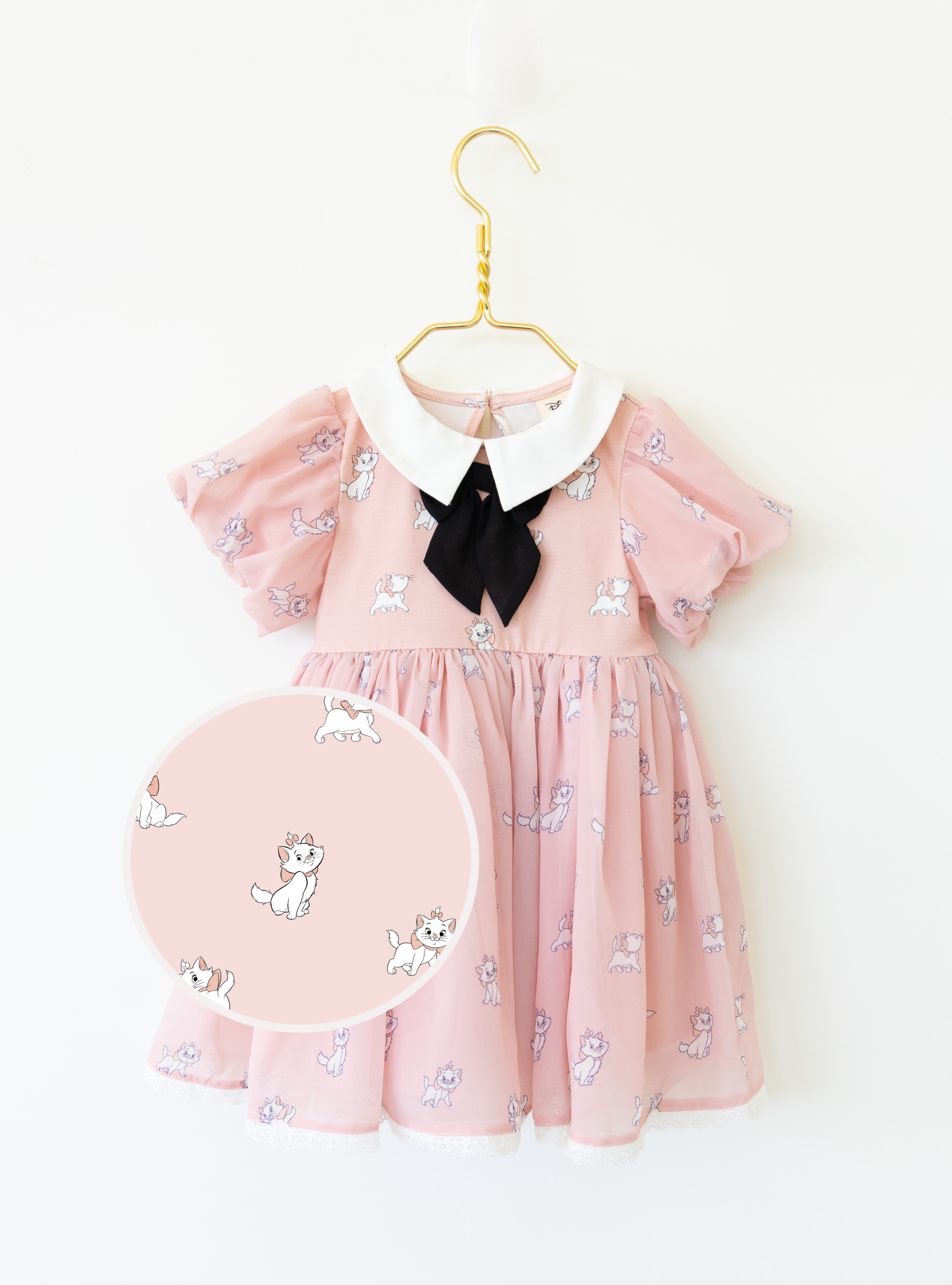 Disney and Taylor Joelle branded Marie Dress with Marie printed all around. This dress has puff chiffon sleeves, and a high waited puff chiffon skirt. Along with that, it has a collar with a black bow, and trim on the bottom of the dress.