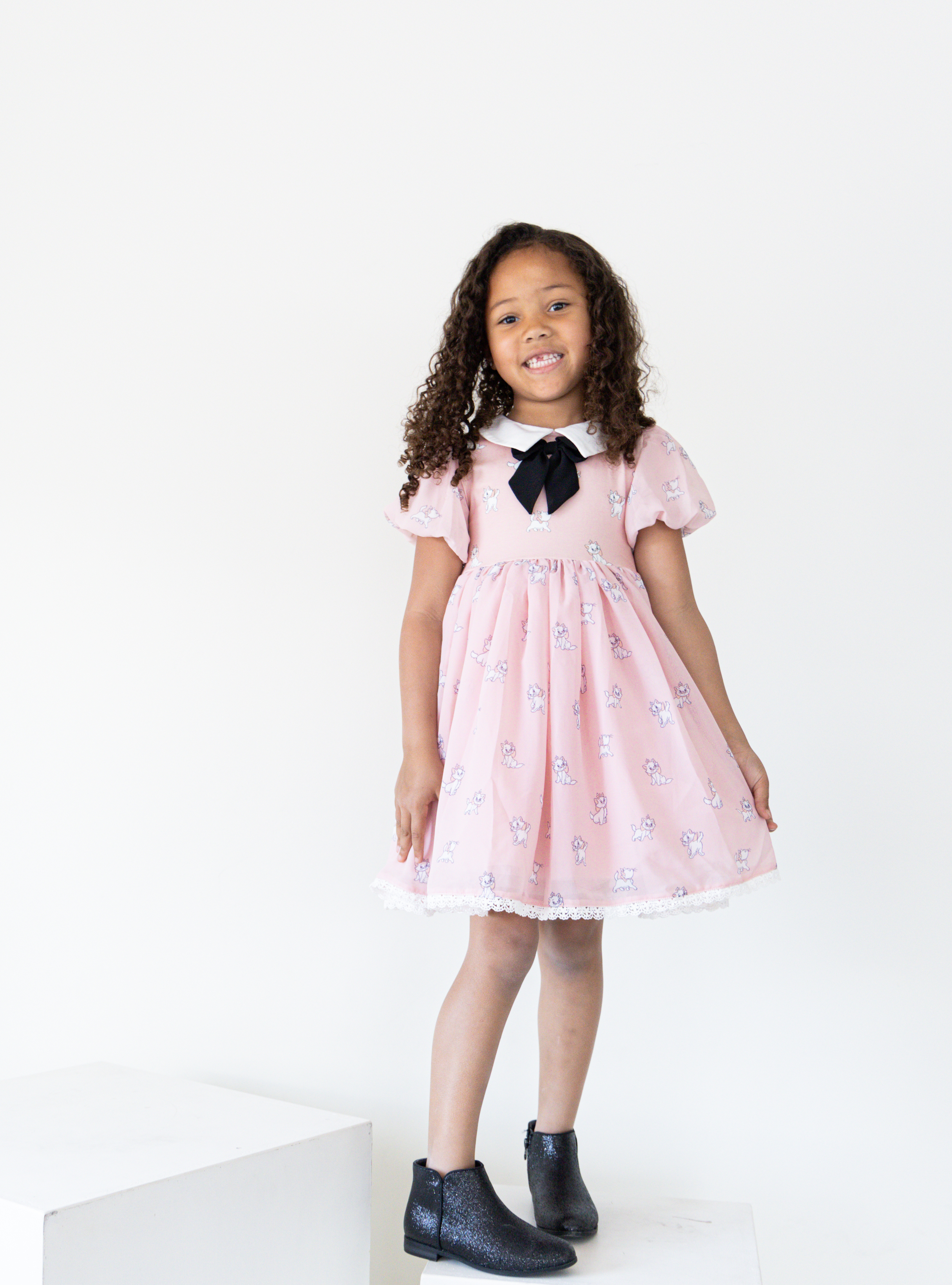 Disney and Taylor Joelle branded Marie Dress with Marie printed all around. This dress has puff chiffon sleeves, and a high waited puff chiffon skirt. Along with that, it has a collar with a black bow, and trim on the bottom of the dress.