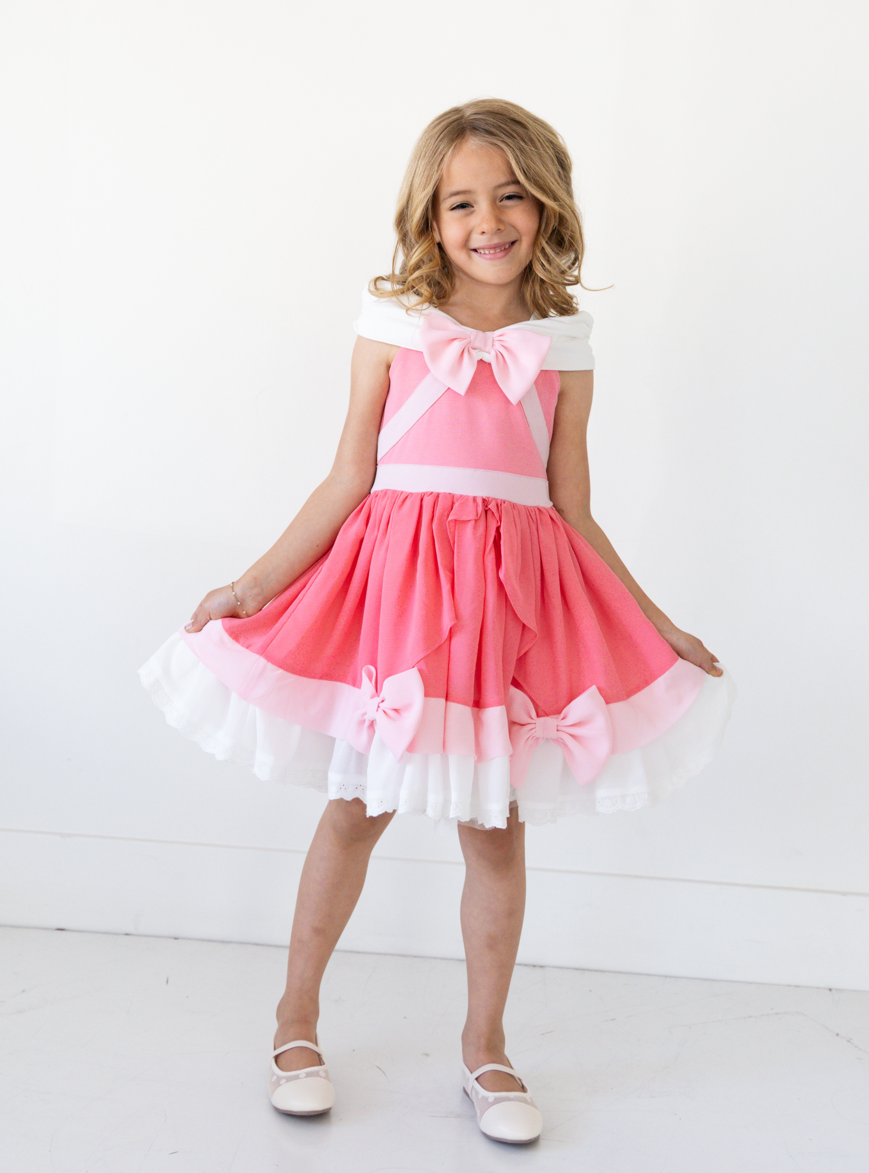 Disney and Taylor Joelle branded Pink Cinderella Dress. This dress is detailed with off the shoulder sleeves, bows, and different pink and white detailing.