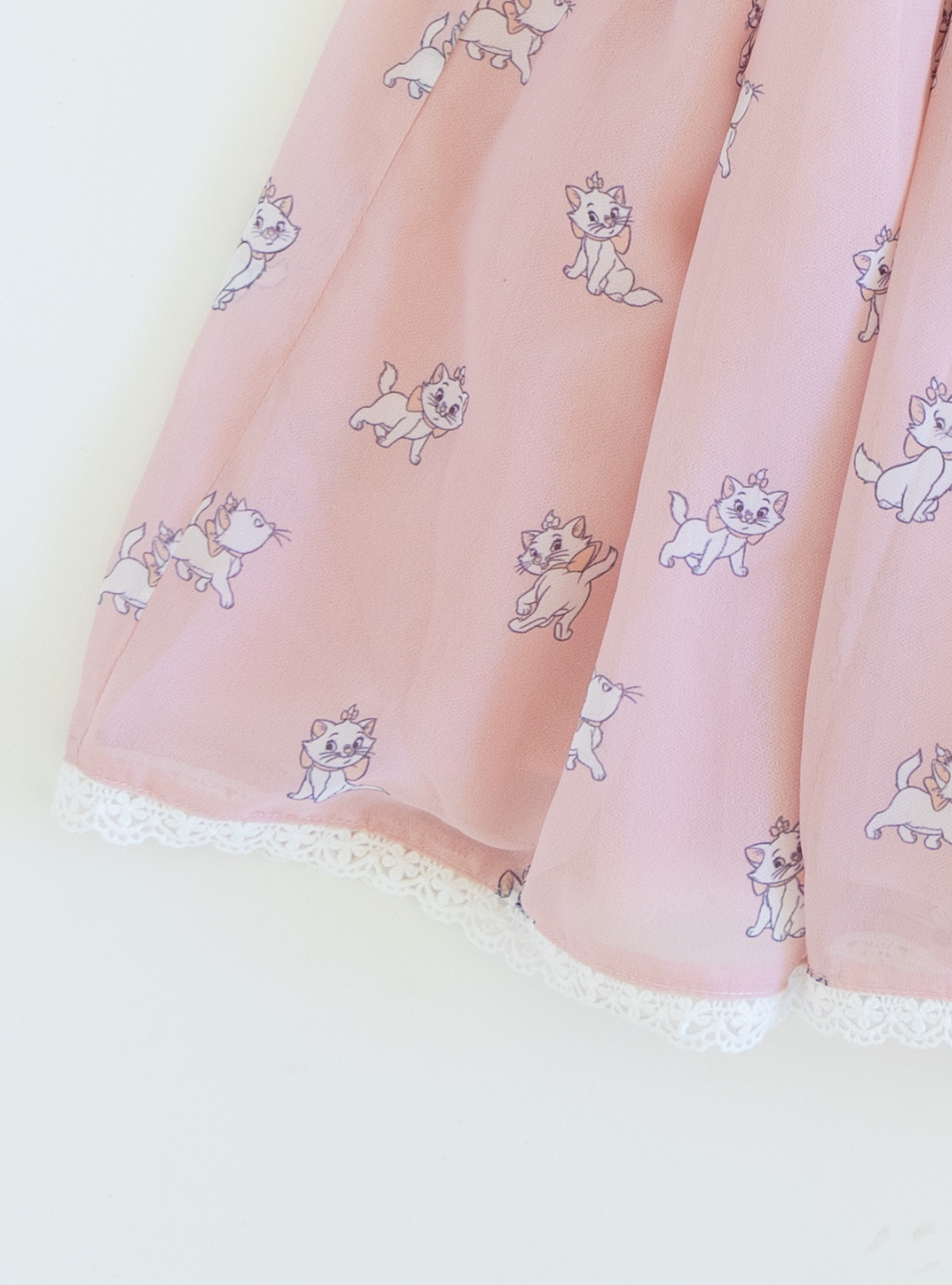 Disney and Taylor Joelle branded Marie Dress with Marie printed all around. This dress has puff chiffon sleeves, and a high waited puff chiffon skirt. Along with that, it has a collar with a black bow, and trim on the bottom of the dress.