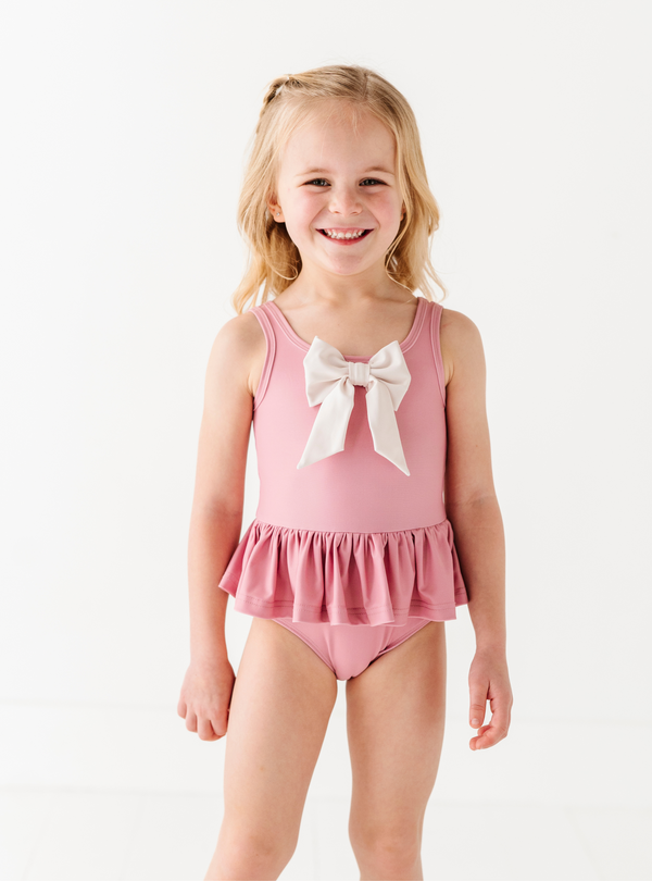 The Blushing Bow One Piece is a sweet addition to your little one's waredrobe, with it's adorable details and cute colors!