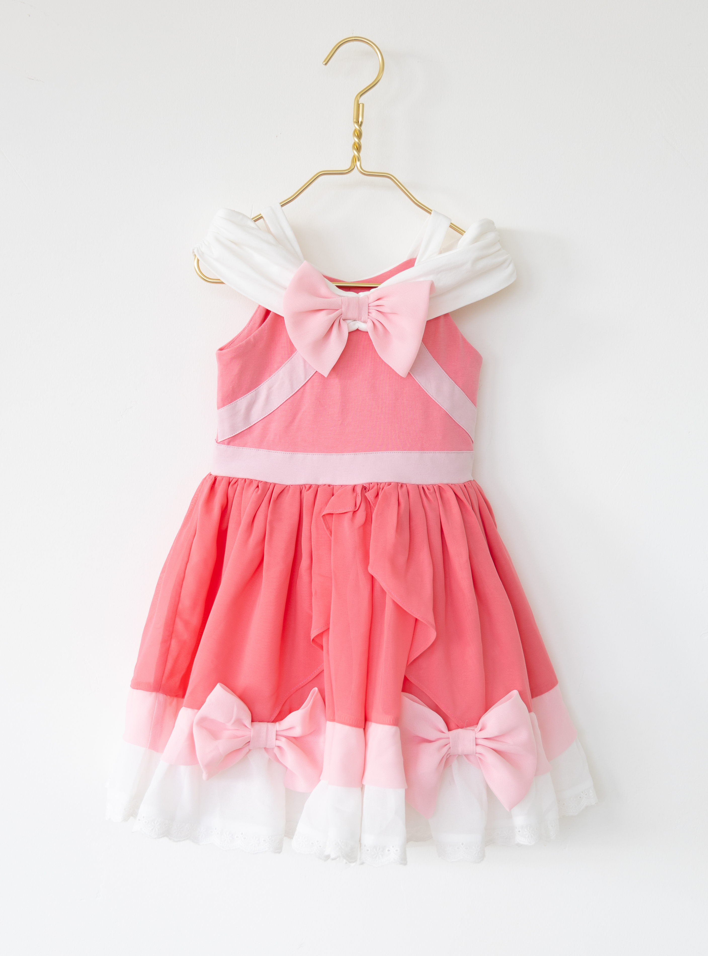 Disney and Taylor Joelle branded Pink Cinderella Dress. This dress is detailed with off the shoulder sleeves, bows, and different pink and white detailing.