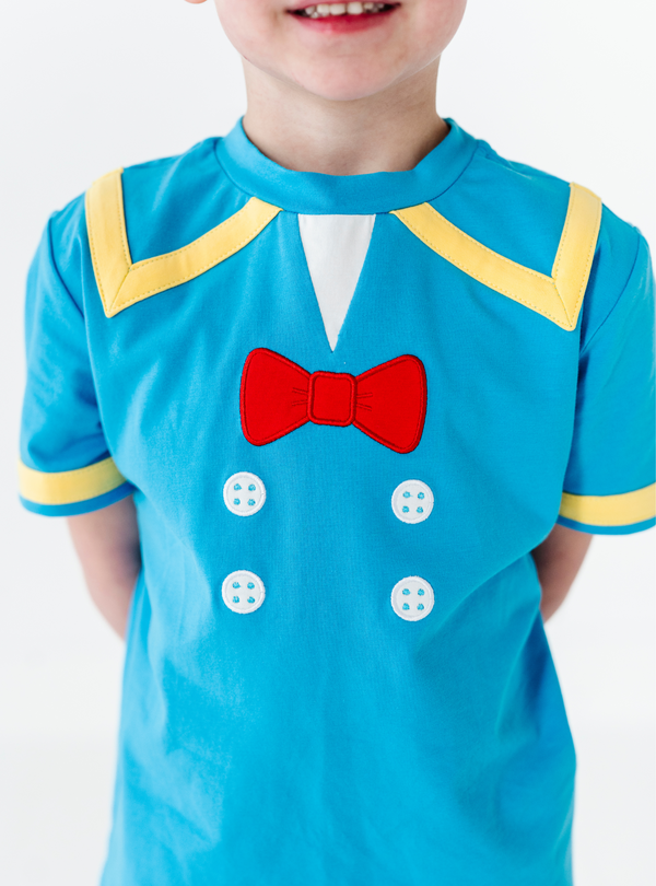 A closer look at the red bow and white faux buttons, with yellow design details on the collar and sleeves.