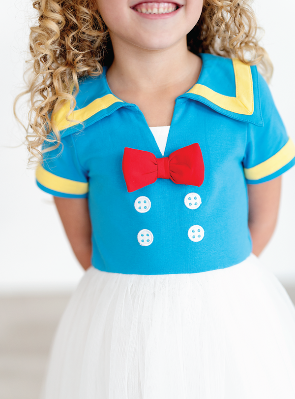 A closer look at the blue and yellow collar, along with a red bow and faux buttons.