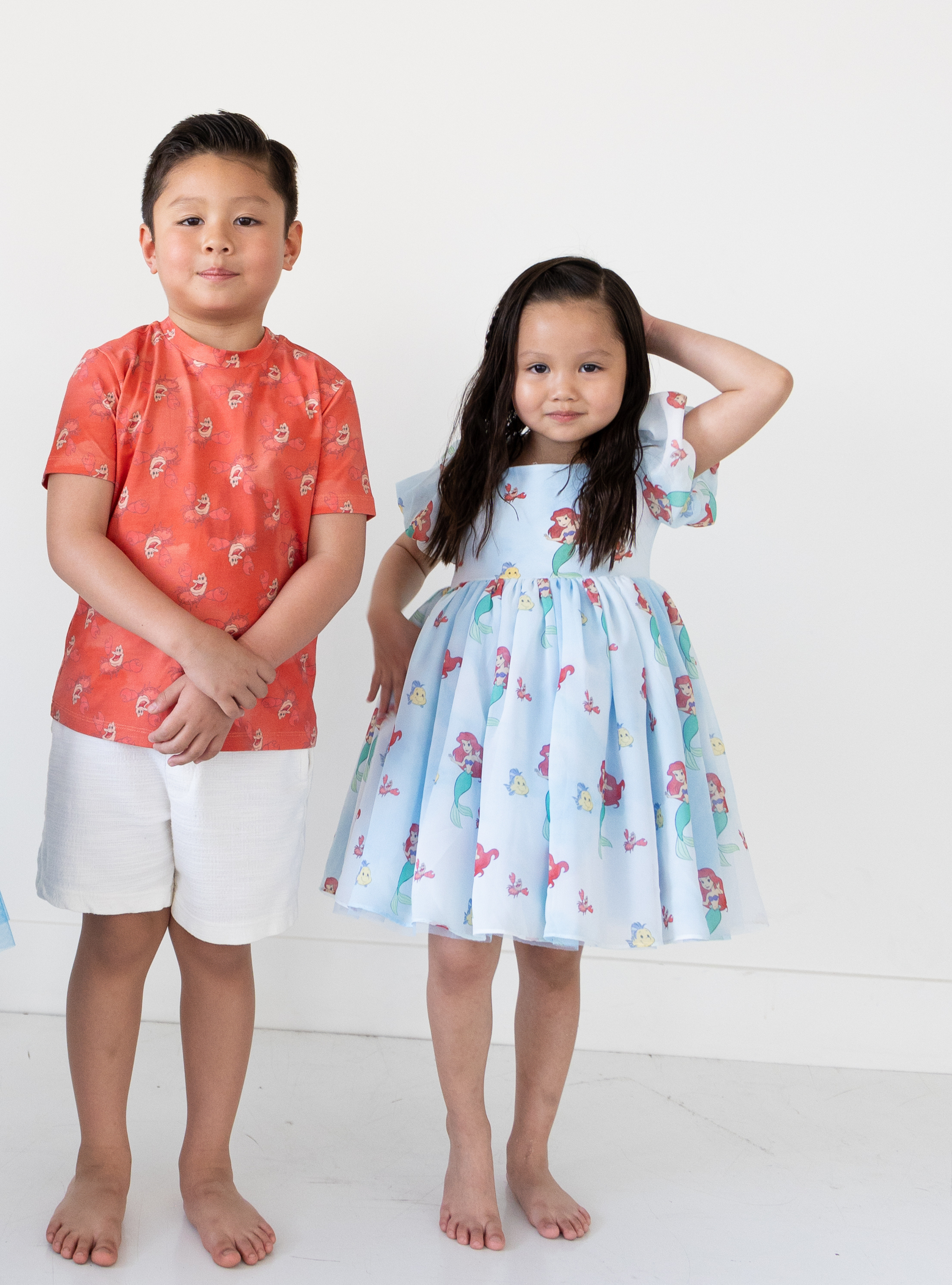 Disney and Taylor Joelle branded Ariel dress with an Ariel, Flounder, and Sebastian print all around. This dress has puff sleeves, and a high waited puff chiffon skirt. Shown with the matching Sebastian tee.