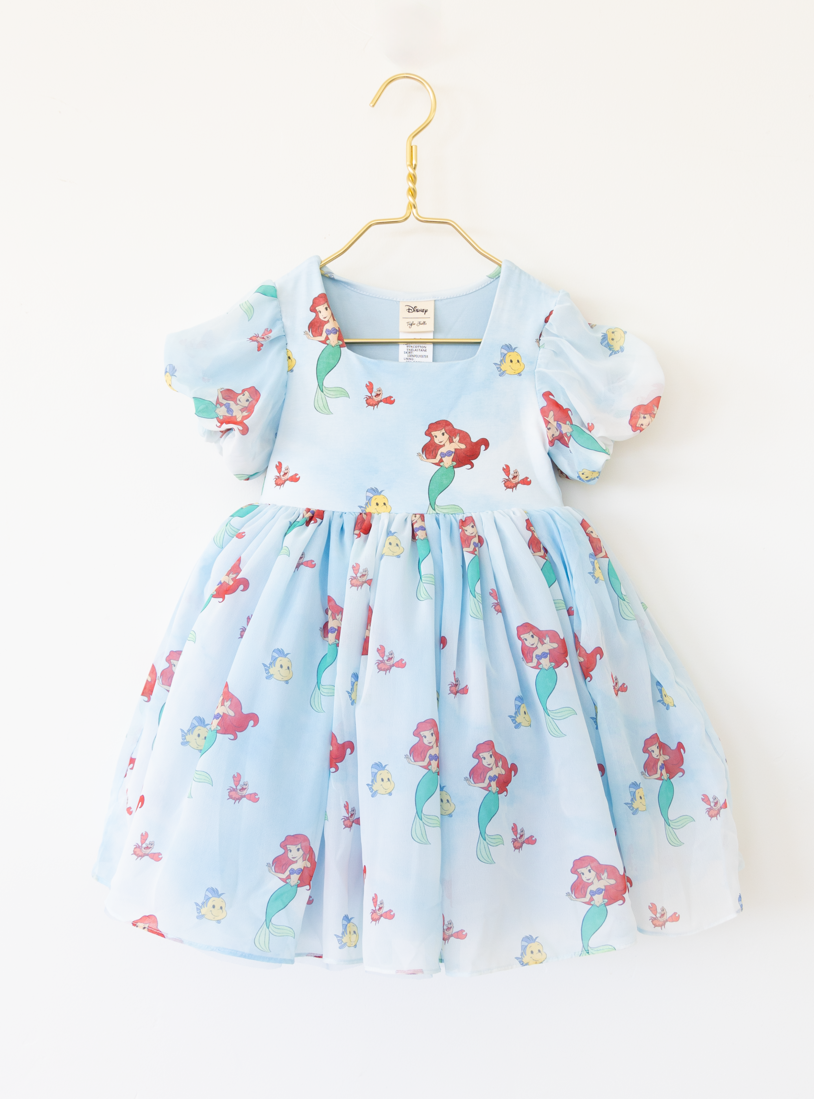 Disney and Taylor Joelle branded Ariel dress with an Ariel, Flounder, and Sebastian print all around. This dress has puff sleeves, and a high waited puff chiffon skirt.