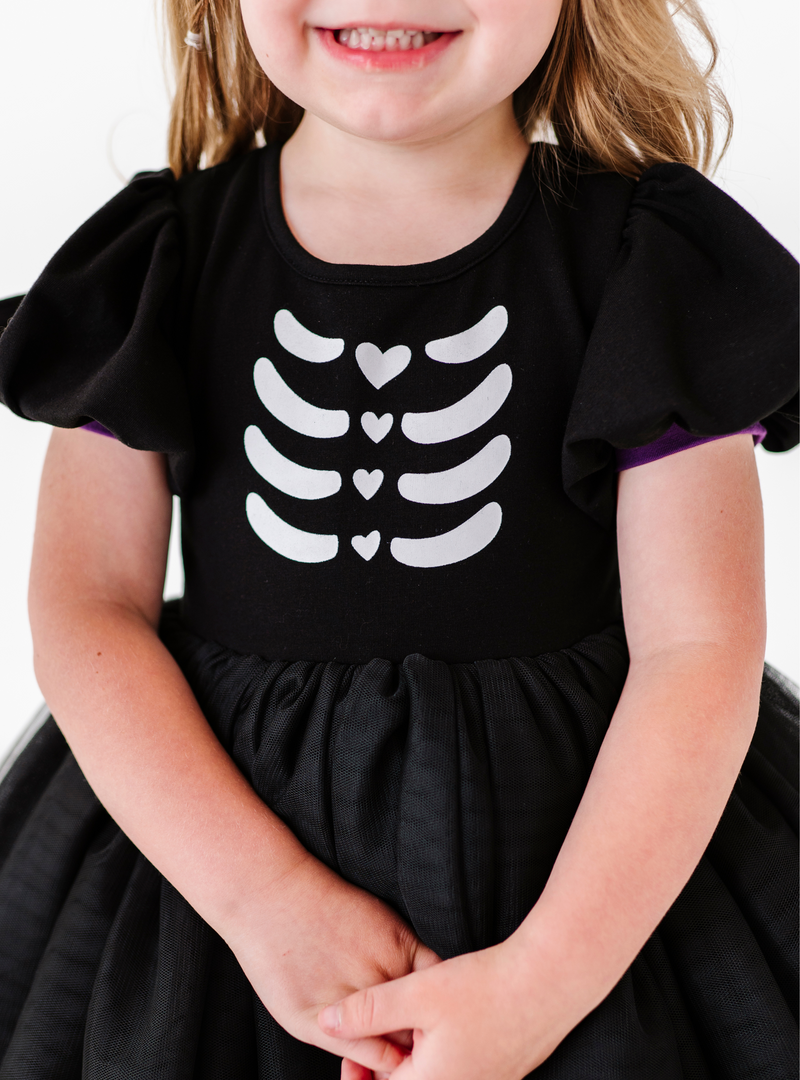 A closer look at the black puffed sleeves with purple detailing as well the skeleton print design on the front!